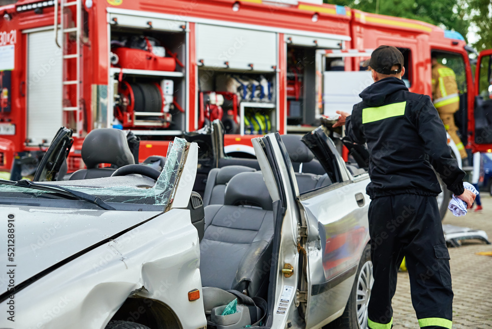 Obraz premium Firefighters during a rescue operation training. Rescuers unlock the passenger in car after accident. Katy Wroclawskie, Poland - May 28, 2022