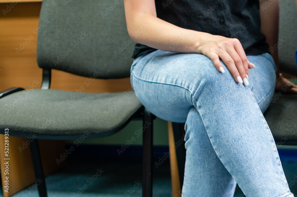 Beautiful tender female hand with long well-groomed fingers on the knee of leg in jeans Beautiful tender female hand with long well-groomed fingers on the knee of leg in jeans