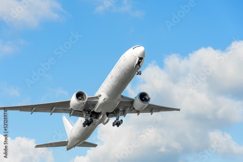 Plane takes off by retracting the landing gear against blue sky background.