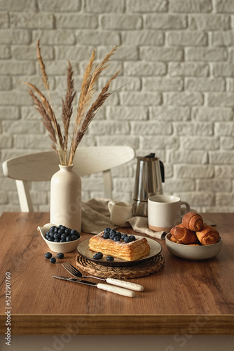 Still life in scandinavian style on a wooden kitchen table. Coffee, homemade cakes and fresh blueberries for breakfast. Concept for good morning wishes. Kinfolk style life. Copy space. Vertical photo
