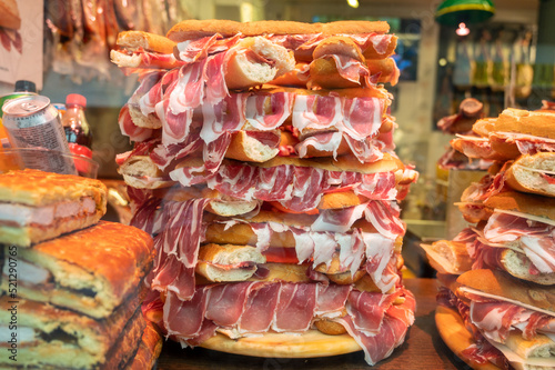 Spanish street food, fresh baked baguette bread with sliced iberian cured ham jamon, bocadillo