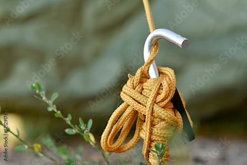 Konstfotografi knots of yellow rope with a hook support the khaki tent