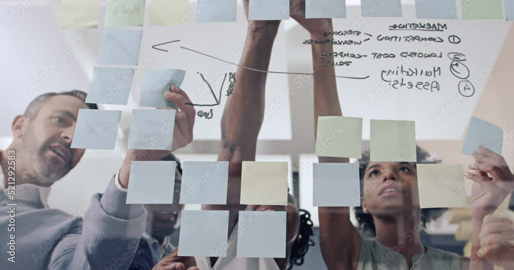 Timelapse of planning, brainstorming and strategy with sticky notes on glass wall in business boardroom meeting. Diverse group of executives with technology talking, writing and analyzng data results
