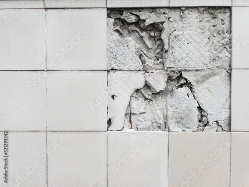A wall with a broken off gray tile from the wall