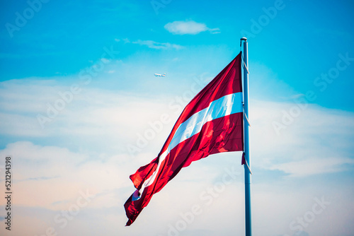 Flag of the Republic of Latvia. Latvian flag waving in the wind against the blue sky.