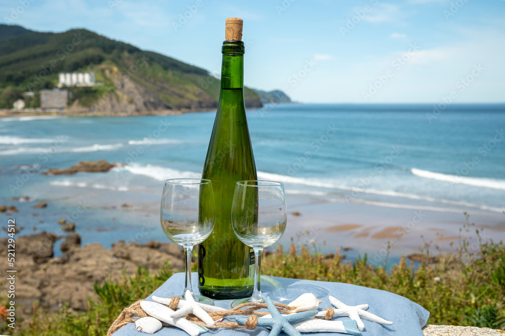 Tasting of txakoli or chacolí slightly sparkling very dry white wine produced in the Spanish Basque Country, served outdoor with view on Bay of Biscay, Atlantic Ocean.