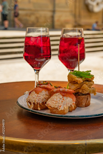 Glasses of cold sangria wine served outdoor with pinchos in bar with view on old street in San Sebastian, Basque Country, Spain