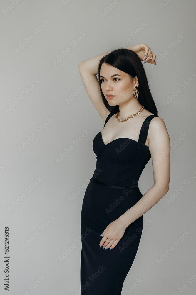 A girl in a black dress stands on a white background A girl in a black dress stands on a white background