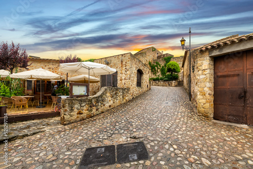 The medieval Spanish village of Pals, Spain, with a sidewalk cafe on it's cobbled damp streets after a summer rainstorm near the Costa Brava coast Fototapet