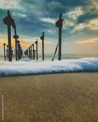 Scenic view of wave bubbles on the beach of India with old pillars during sunset photo