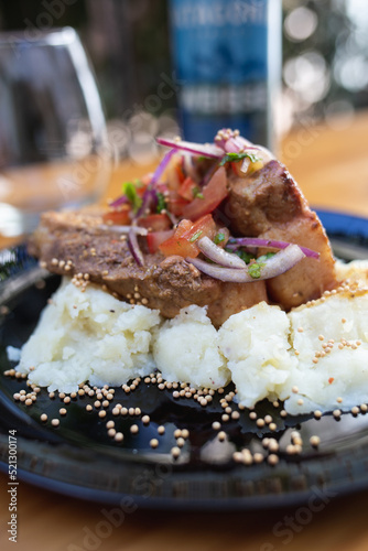 dish with meat, mashed potatoes and vegetables, glass and beer on the table