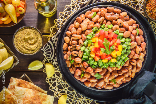 Arabic Cuisine: Egyptian traditional dish "Ful medames". Middle Eastern breakfast with cooked fava beans and fresh vegetables. Served with olive oil, pickles, pita bread, cumin and lemon. 
