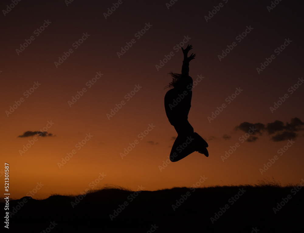 silueta de mujer saltando en un atardecer. Concepto de personas y estilos de vida. silueta de mujer saltando en un atardecer. Concepto de personas y estilos de vida.