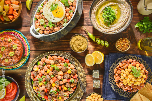 Arabic Cuisine: Varieties of traditional Egyptian beans dishes consisting of beans with sausage,  tahini ,eggs, chickpeas, olive oil and also with spicy tomato sauce. Top view with close up.