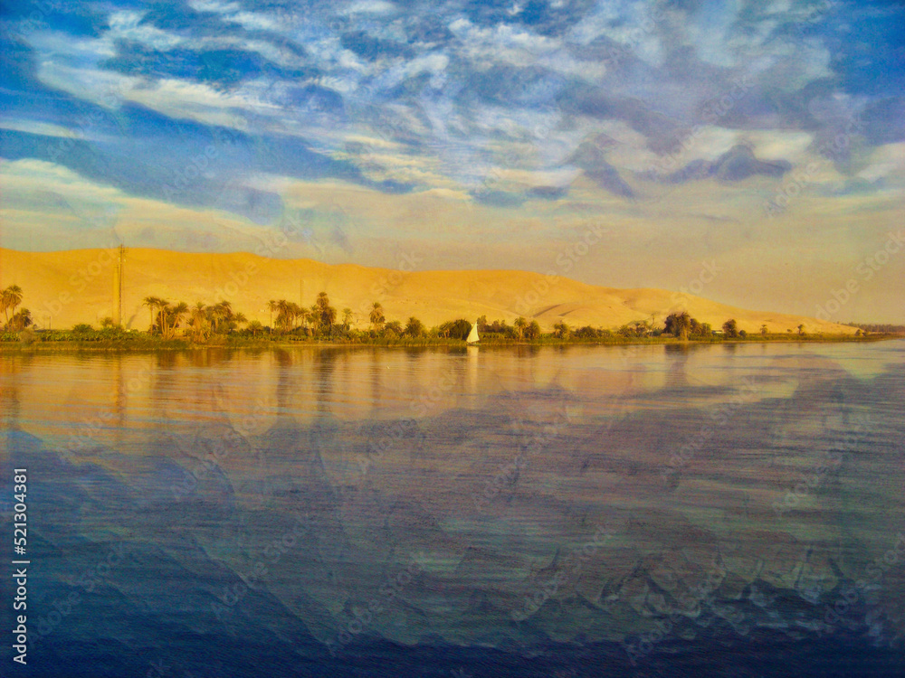 Fototapeta premium Along the Nile River in Egypt, with blue water, blue sky, and the bright white sail of a small boat. With a thin strip of greenery and dunes behind the line of green.