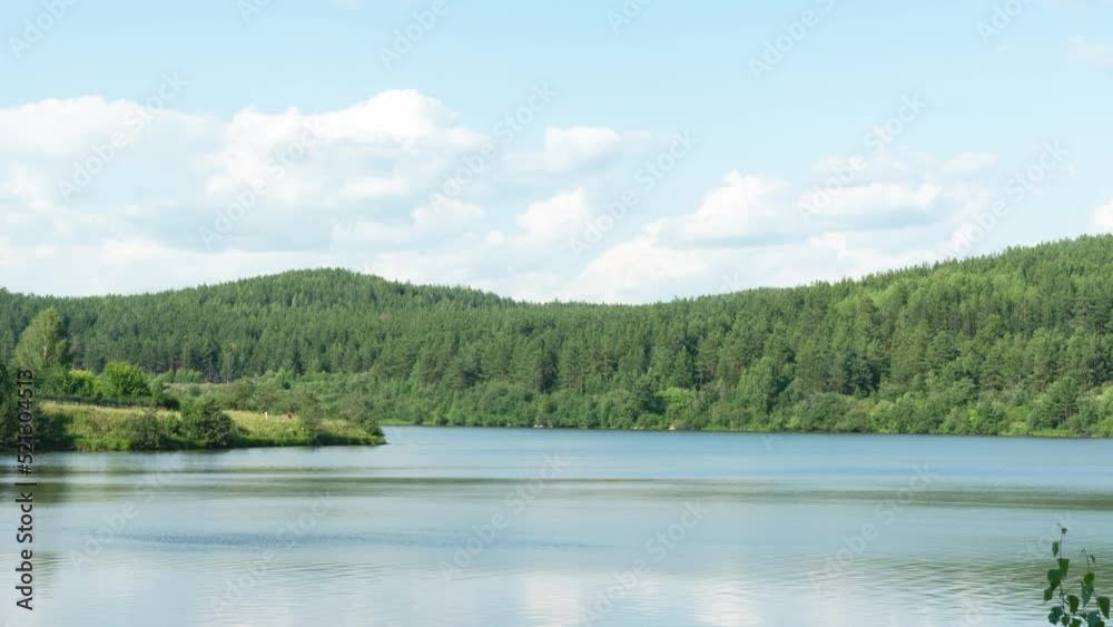 Beautiful clouds move over a body of water and wooded mountains on a summer sunny day Beautiful clouds move over a body of water and wooded mountains on a summer sunny day