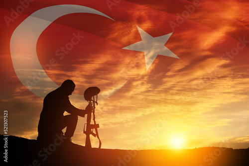 Silhouette of soldier kneeling with his head bowed against the sunrise or sunset and Turkey flag. Concept of crisis of war and conflicts. Greeting card for Turkish Armed Forces Day, Victory Day.