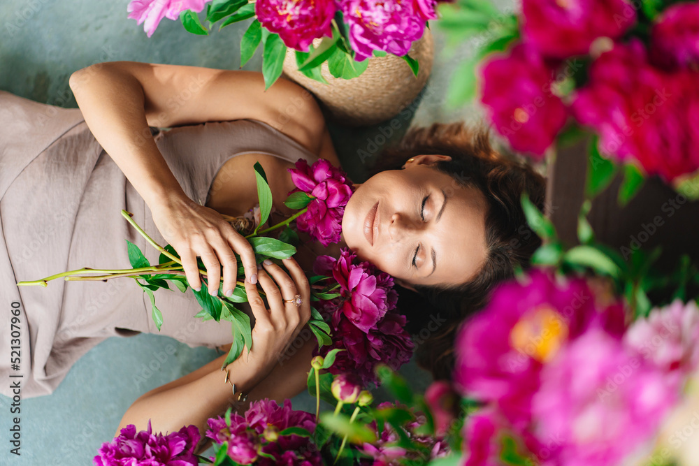 an attractive woman on the floor with a bouquet of peonies.