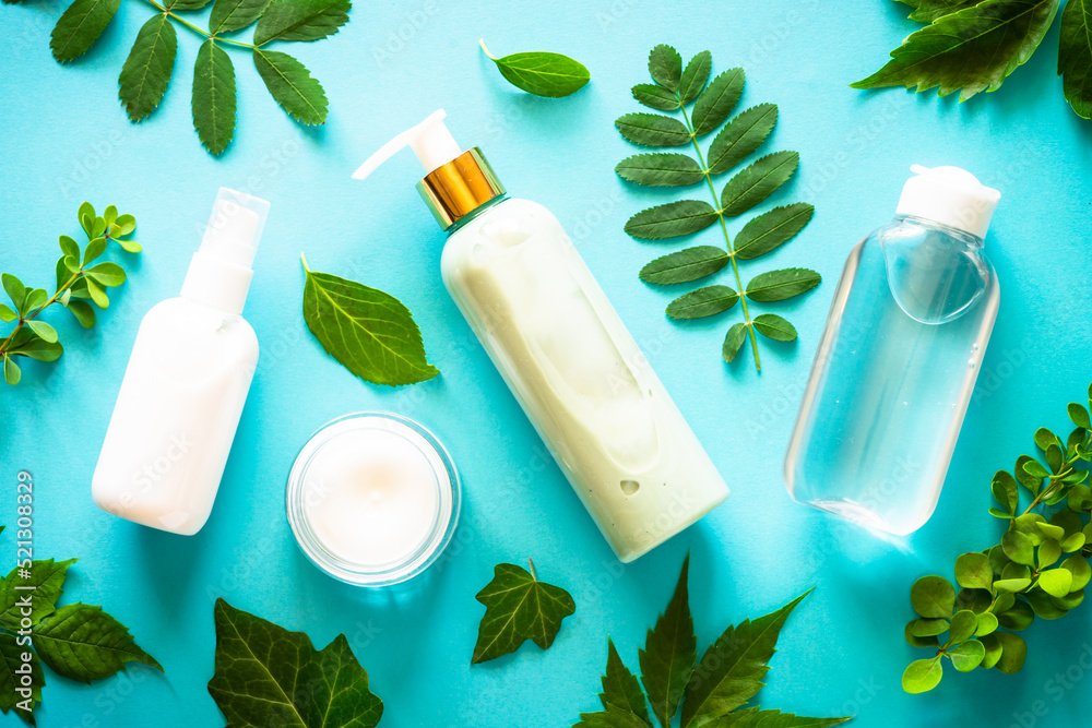 Natural cosmetics concept. Skin care product, cream, serum, soap, mask with green leaves. Flat lay image on blue with space for your text. Natural cosmetics concept. Skin care product, cream, serum, soap, mask with green leaves. Flat lay image on blue with space for your text.