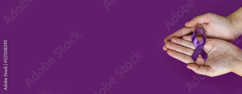 World Alzheimer's day. September 21. International Epilepsy Day. Adult hands holding purple ribbon on purple background. World Lupus Day and world cancer