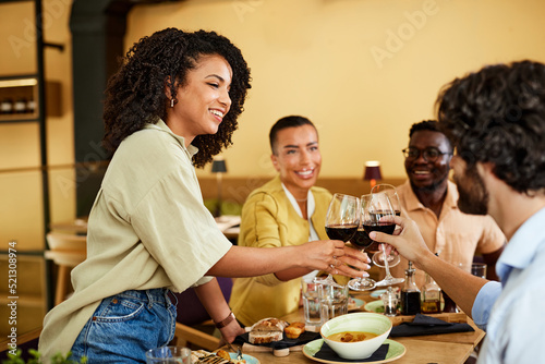 A group of tipsy friends toasts with red wine during a dinner party at a restaurant.