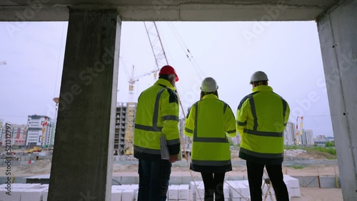 three civil engineers are viewing construction site of residential or nonresidential building photo