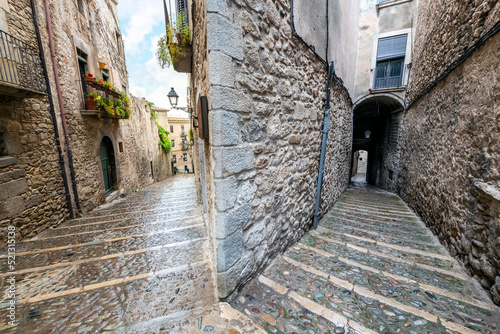 A fork in the road as two narrow stone alleys descend in different directions in the medieval Jewish Quarter of the historic Spanish town of Girona, Spain. photo