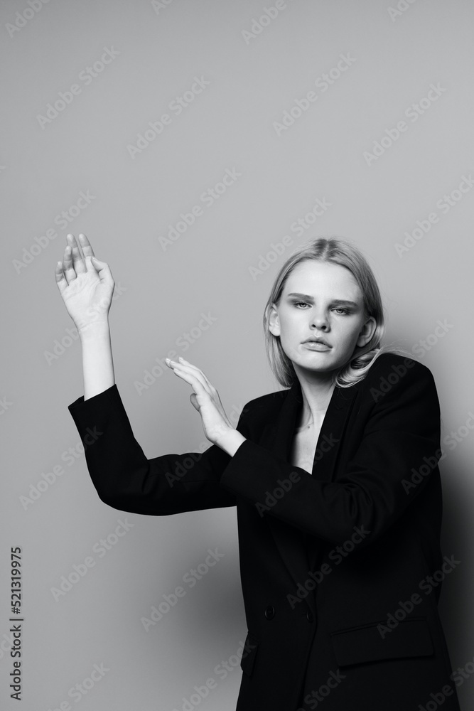 Fashion model girl posing with her hands up in the studio in black and white style in a classic jacket Fashion model girl posing with her hands up in the studio in black and white style in a classic jacket