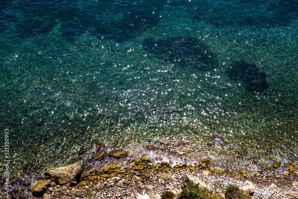 View of the transparent water of the sea on the coast from the rocky cliffs, natural background.