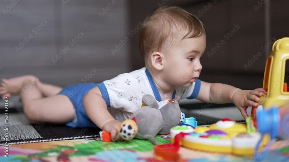 Sweet little kid lying on the floor crawling closer to his toys. Lovely child choosing car among other toys. Close up. Sweet little kid lying on the floor crawling closer to his toys. Lovely child choosing car among other toys. Close up.