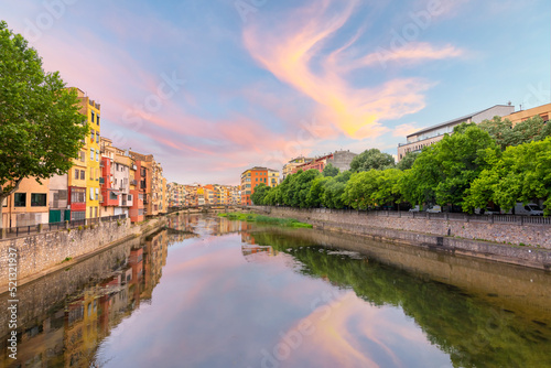 The Spanish town of Girona bathed in colorful light at sunset on the River Onyar, in the Catalonian Costa Brava region of Southern Spain.