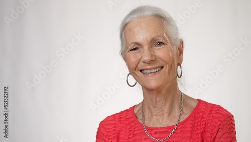 Portrait of smiling happy elderly woman on solid white background.