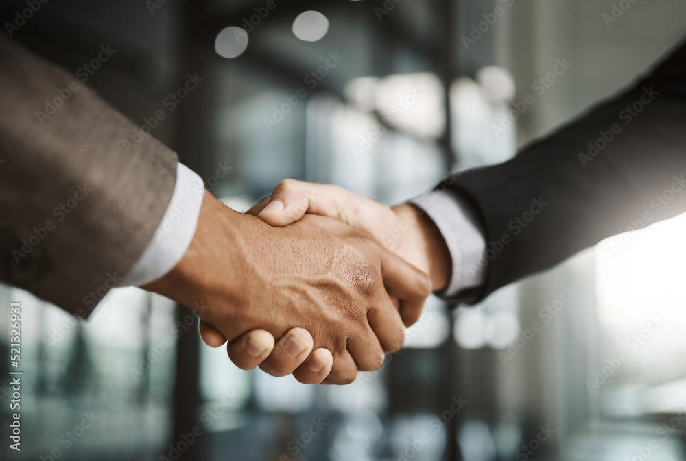 Closeup of business men giving handshake, hiring an employee and welcoming to a company in a meeting in a modern office together. Corporate professionals making deals, agreements and showing teamwork