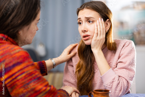 Woman comforting her female friend who sitting at table and feeling depressed. photo