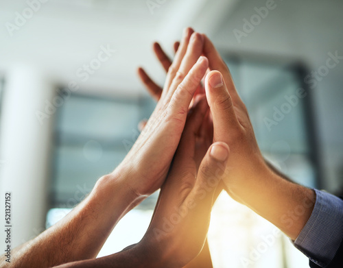 High five of a diverse group of businesspeople celebrate, unite and support each other. Closeup of a multiethnic corporate professional team hands touching showing success inside a startup office
