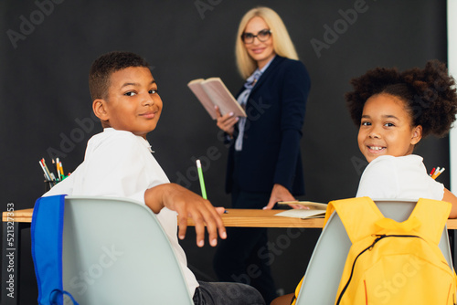 A girl and a boy, African-American school children, solve problems with the teacher during a lesson. Back to school.