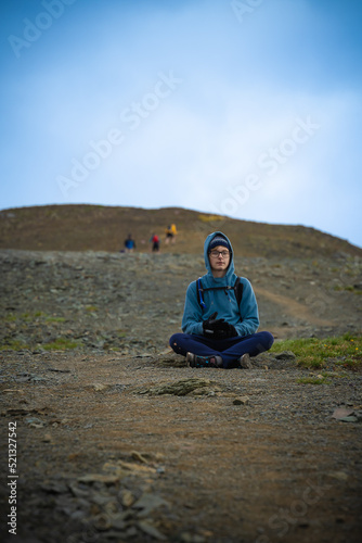 Young man sitting in yoga pose on mountain hike