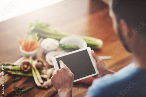 Closeup of hands of man holding a tablet to search a recipe, do research or look for ingredients while cooking dinner, lunch or breakfast. Scrolling online, browsing app and searching for meal ideas