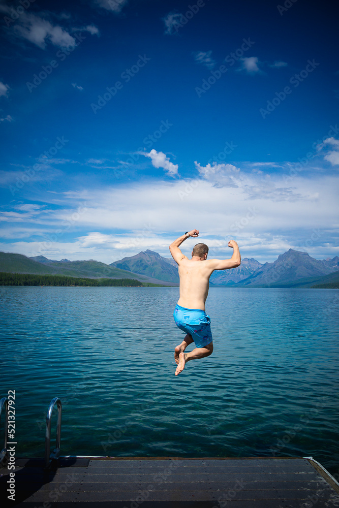 man jumping into a mountain lake