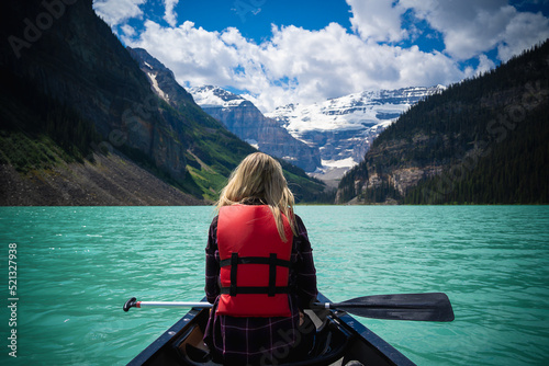 Slika na platnu Blonde woman on a canoe in Lake Louise