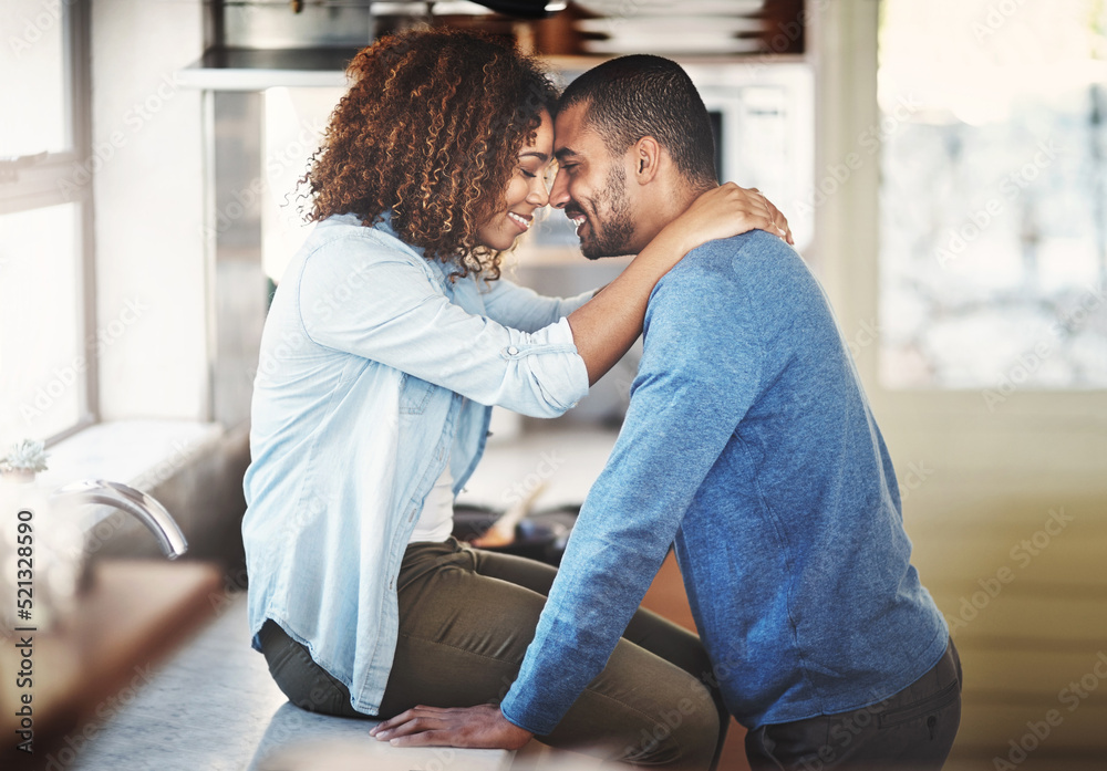 Young happy couple hugging and having a romantic moment in a kitchen at home. Relaxed boyfriend and girlfriend talking while embracing and bonding, enjoying their time together in a new apartment Young happy couple hugging and having a romantic moment in a kitchen at home. Relaxed boyfriend and girlfriend talking while embracing and bonding, enjoying their time together in a new apartment