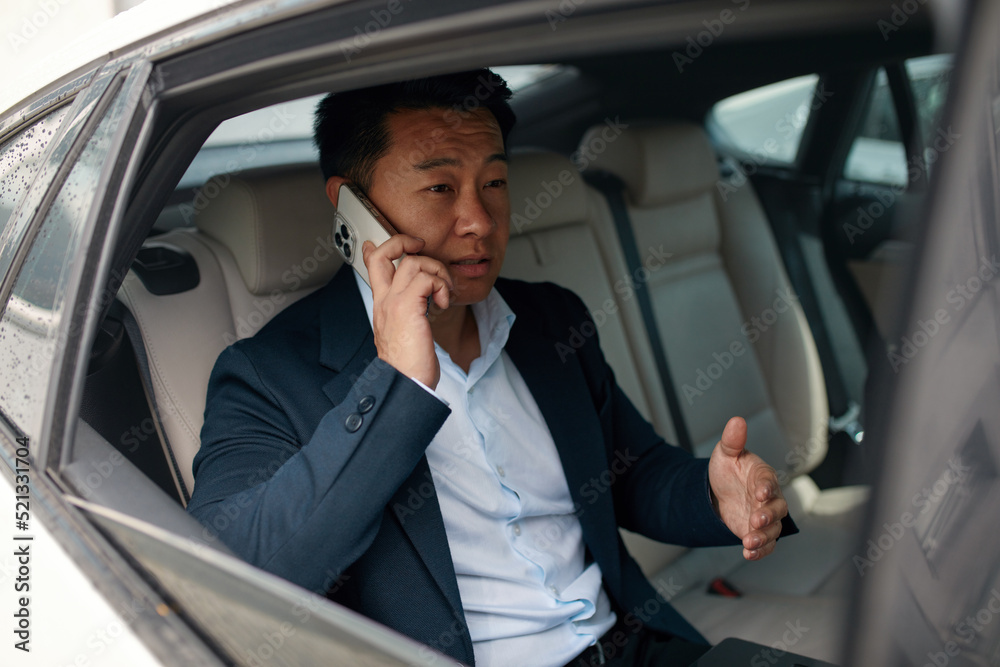 Busy Asian Businessman Calling Smartphone on Car Back Seat. Pensive man in taxi. Transport, Business Trip, Technology and People Concept 