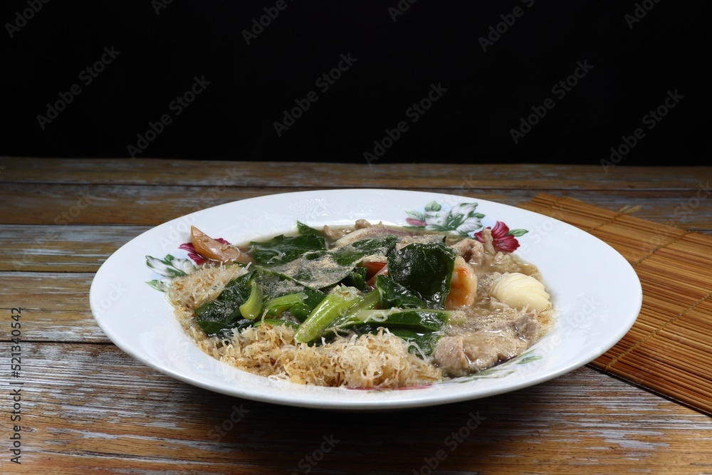 Fried rice noodle mixed with seafood and fresh Chinese kale in thick gravy sauce serving on the plate. Famous street food menu in Asia. 