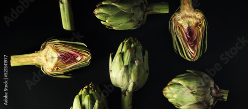 Raw artichokes on dark back...