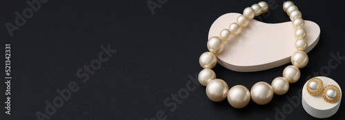 Stylish pearl jewellery on black background with space for text