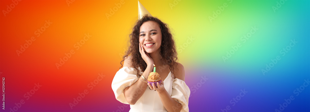 Beautiful African-American woman with birthday cake on rainbow background