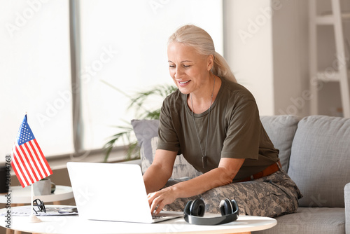 Mature female soldier using laptop at home