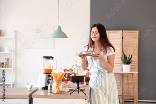 Принти на полотні Young Asian woman holding plate with pumpkin soup after watching cooking video t