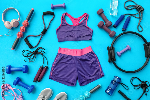 Female sportswear and different equipment for pilates on blue background