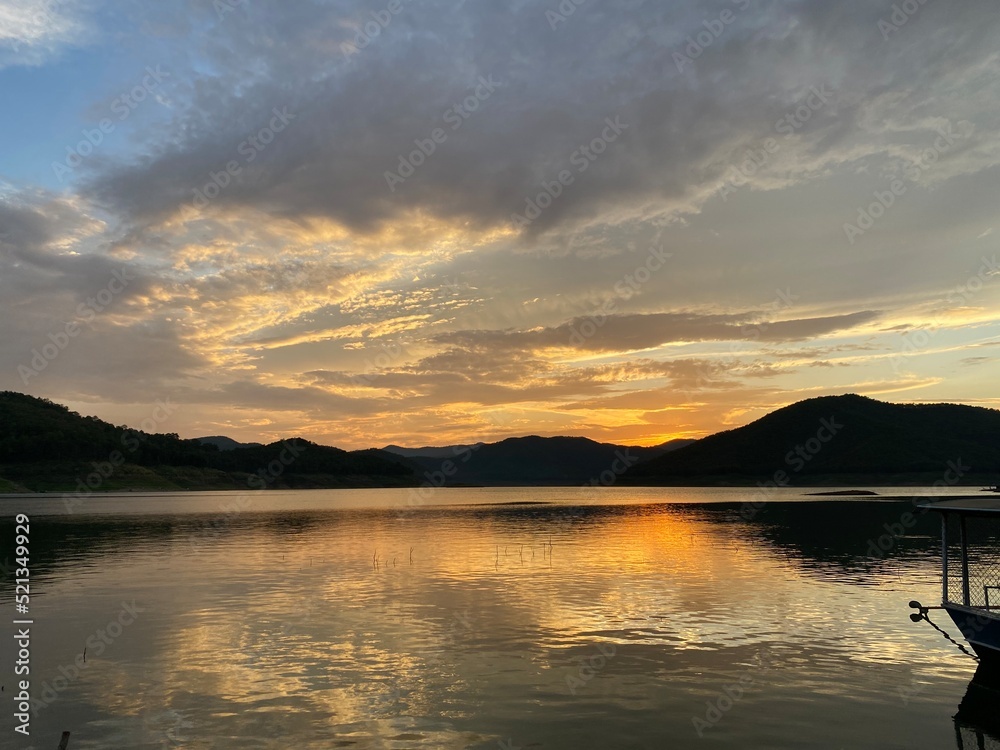 Mountains and sunset golden sky above dam reservoir